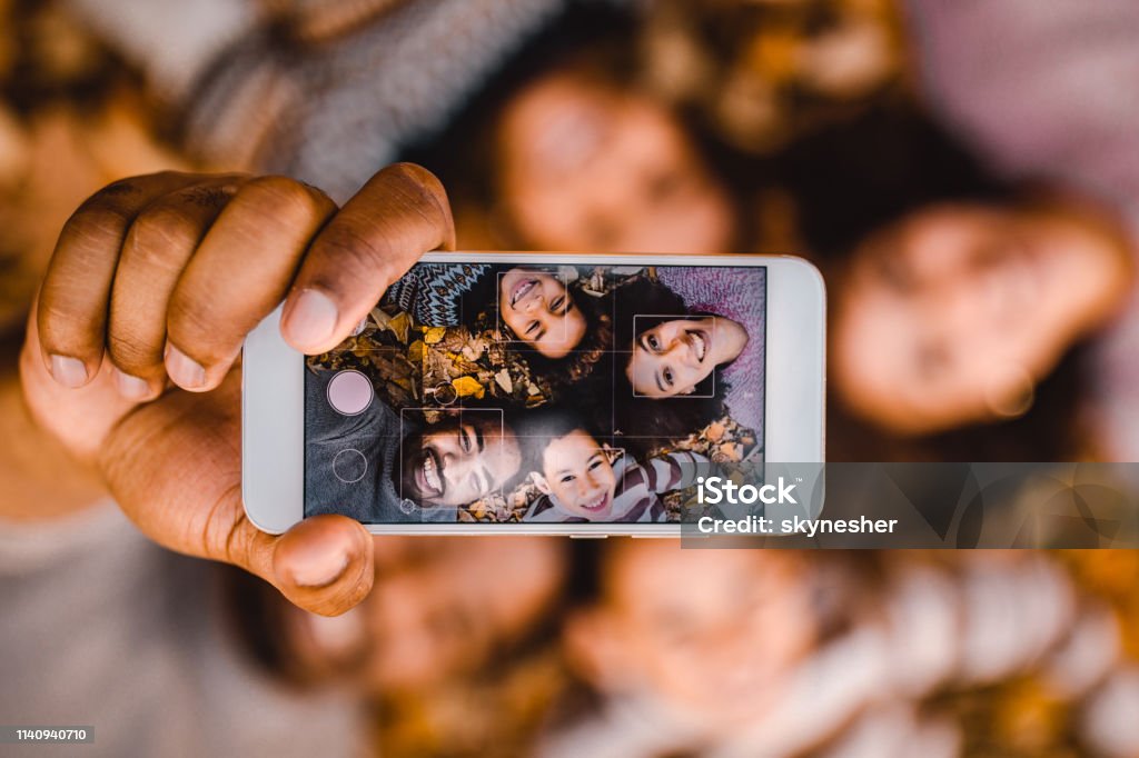 Close-up van Happy Black Family het nemen van een selfie met mobiele telefoon in de herfstbladeren. - Royalty-free Familie Stockfoto