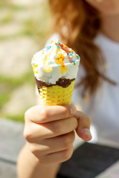 istock Hand holds ice cream in a waffle cone in summer under the sun. Selective focus 1140951576