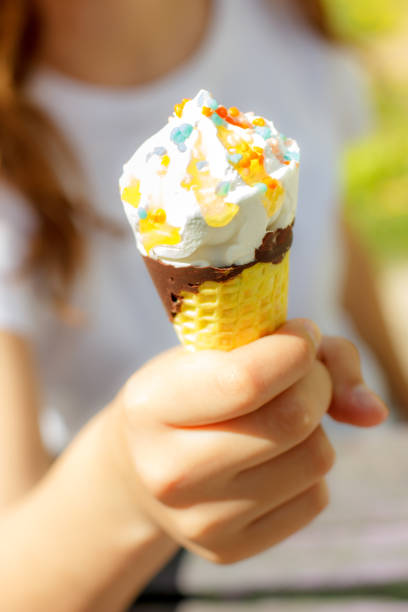 istock Hand holds ice cream in a waffle cone in summer under the sun. Selective focus 1140952340