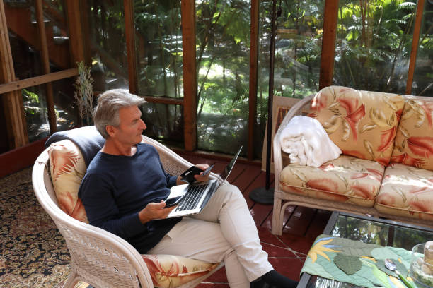 man relaxes at home while online shopping - using laptop contemplation accessibility contemporary imagens e fotografias de stock