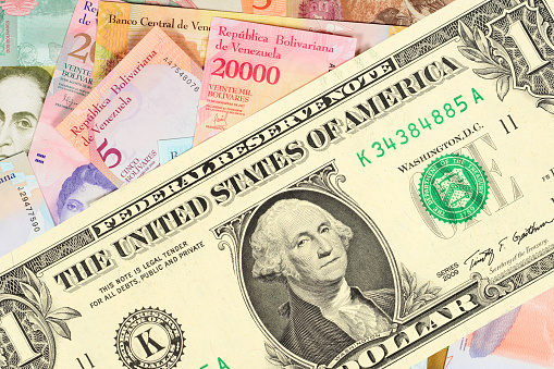 Gran billete de un dólar contra el trasfondo de muchos billetes pequeños venezolanos. El concepto de hiperinflación en Venezuela. Cerrar fondo. photo
