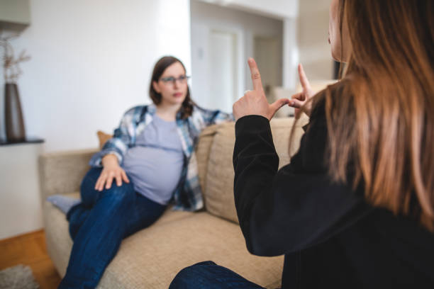 istock Young women talking in sign language while relaxing at home 1140970657