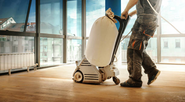 Hardwood floor restoring. Closeup side view of an unrecognizable handyman using a sanding machine to remove the surface layer of a solid oak hardwood floor in a spacious living room. sand paper stock pictures, royalty-free photos & images