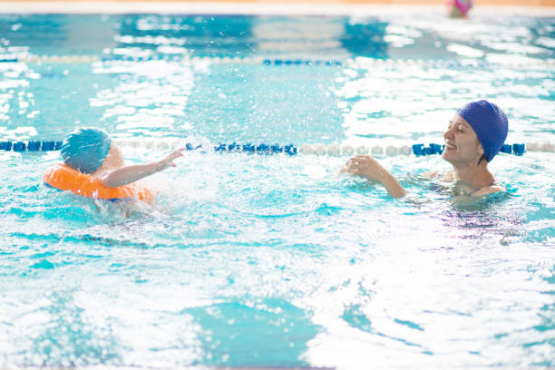 istock Mom and son having fun playing in the swimming pool 1140973197
