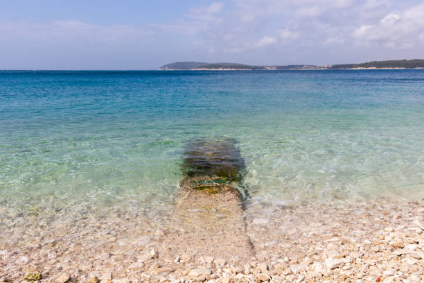 Transparent waters and small round rocks at Ambrela Beach in Verudela near Pula, Croatia