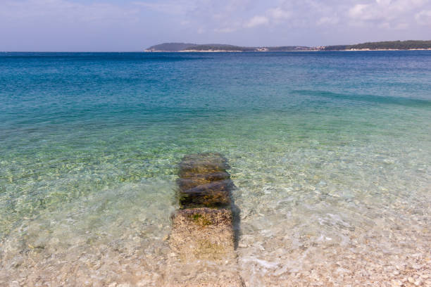 Transparent waters and small round rocks at Ambrela Beach in Verudela near Pula, Croatia