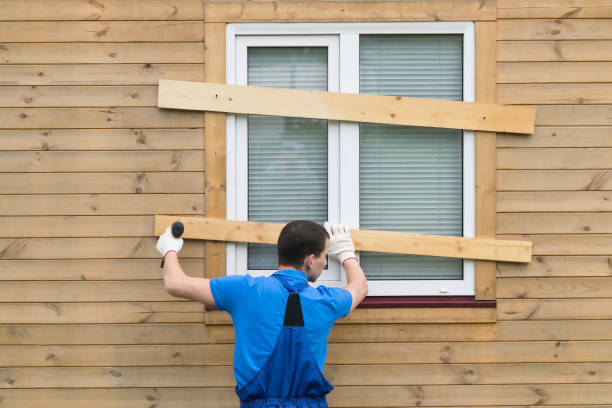 a man in coveralls closes the windows with boards to protect the house during a long departure and hurricane a man in coveralls closes the windows with boards to protect the house during a long departure and hurricane work tool nail wood construction stock pictures, royalty-free photos & images