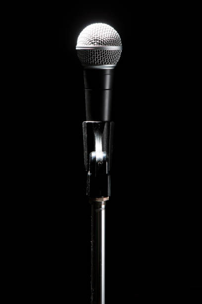 istock Black modern microphone on stand, black dark background. Accentuated shapes with light. 1140979123