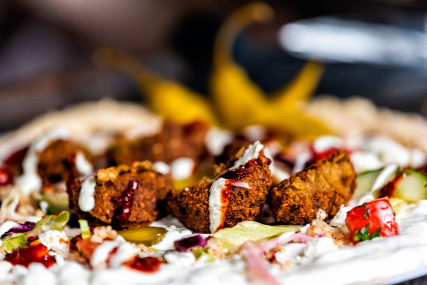 Macro closeup of falafel wrap with chickpea meat fried balls and sauce with vegetables and bread