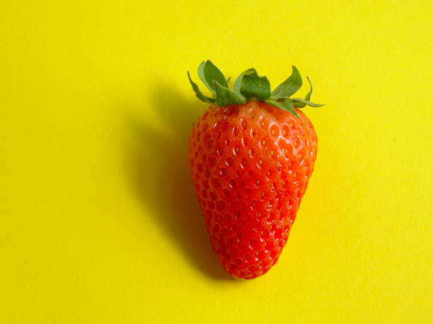 istock Isolated Strawberry, lighted with a warm light  on a bright yellow background 1140983179