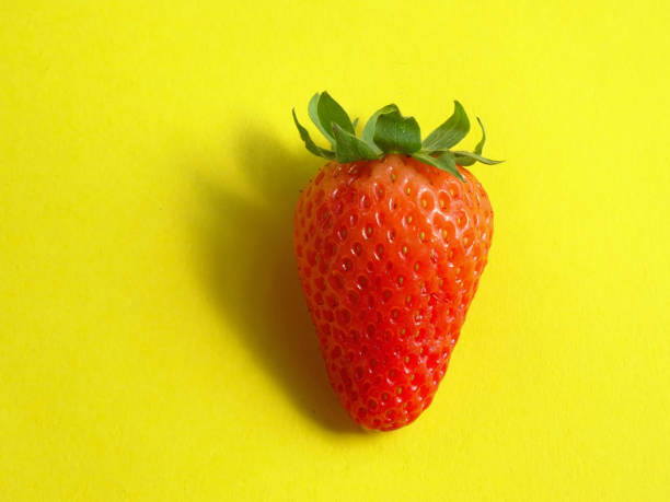 Isolated Strawberry, lighted with a warm light  on a bright yellow background