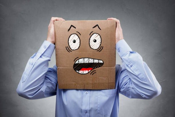 Businessman with cardboard box on his head showing a shocked and surprised expression expression concept for failure, surprise, fear, anxiety or disbelief