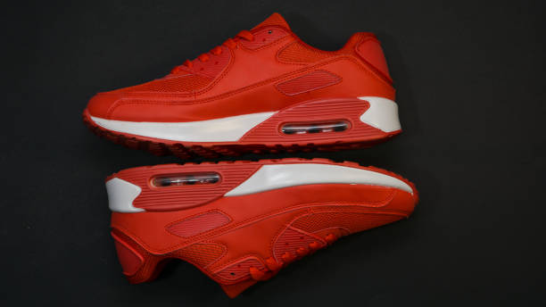 Red sneakers, with white sole, there is a shadow, close-up on a black background