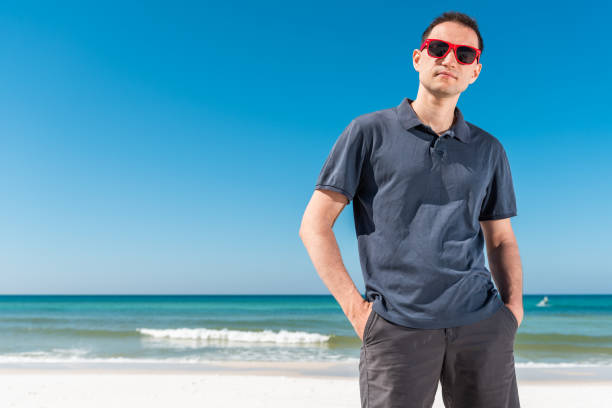 istock Young handsome attractive man hipster millennial serious face closeup on beach during sunny day with red sunglasses in Florida panhandle with ocean hands in pockets 1140994579