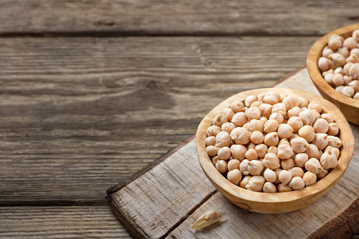 Nutrient-dense food - raw chickpeas grains in bowl on a wooden rustic table. Copy space for text.