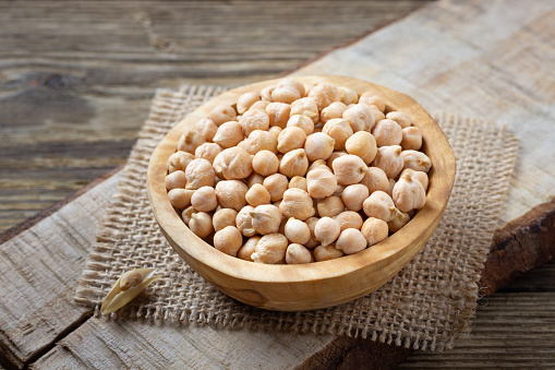 Nutrient-dense food - raw chickpeas grains in bowl on a wooden rustic table. Copy space for text.