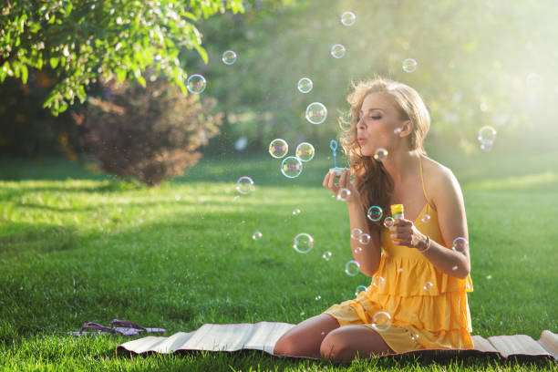 istock Young woman having fun and blowing bubbles outdoors 1141002288