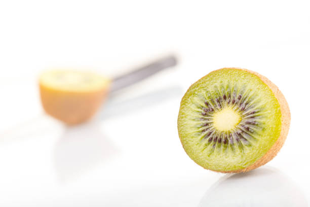 Green fresh kiwi fruit cut into half and knife on a white background.