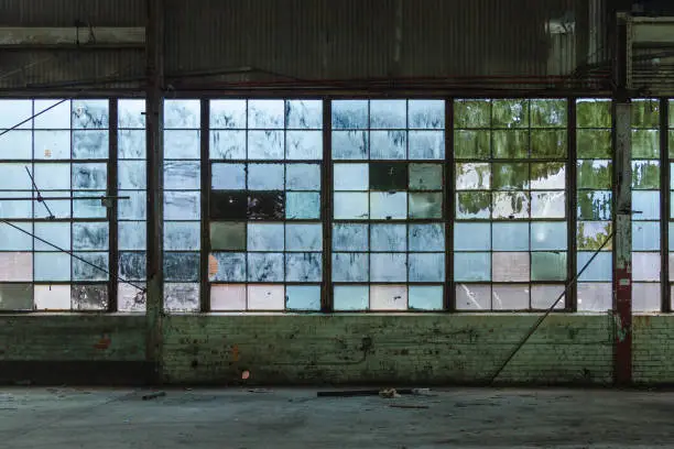 Blue tinted windows in an abandoned brick factory in a depressed urban area