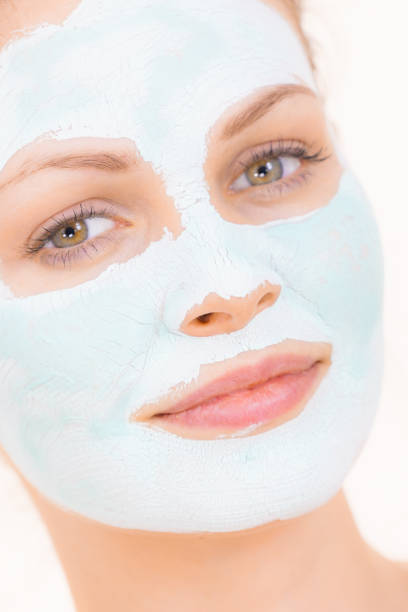 istock Girl with white green mud mask on face 1141005619