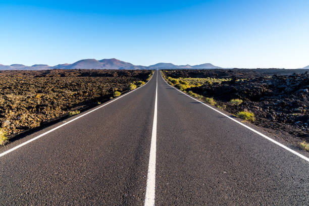 istock Spain, Lanzarote, Endless bolt upright asphalt road to magic red volcano mountains 1141007412