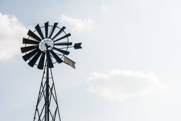 istock Old-fashioned metal wind pump against pale blue sky with white clouds. 1141007700