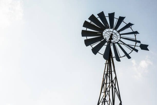 istock Old-fashioned metal wind pump against pale blue sky. 1141008084