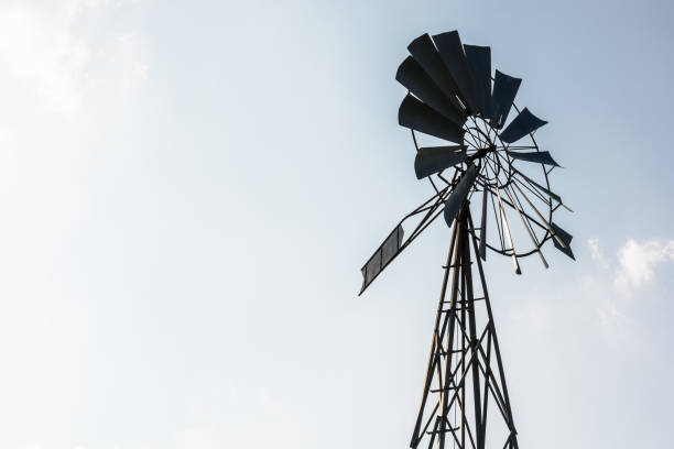 istock Old-fashioned metal wind pump against pale blue sky. 1141008467