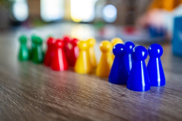 istock Multicolored plastic chips from a children's board game stand on a wooden table, in natural light, on a blurred background. 1141009220