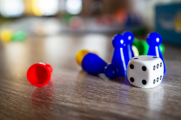 istock Dice and multi-colored plastic chips from a children's board game, lie on a wooden table in natural light, on a blurred background. 1141009639