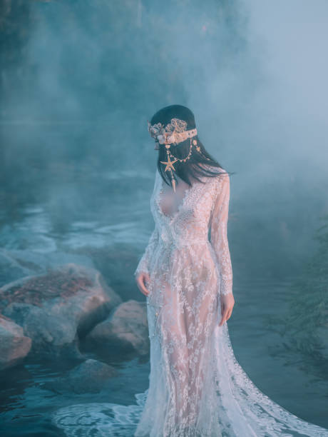 istock Nymph, walks in the river which was tightened by a thick, impenetrable fog. She has a white vintage, lacy dress. Feast of Ivan Kupala. The girl turned her face away from the camera 1141009733