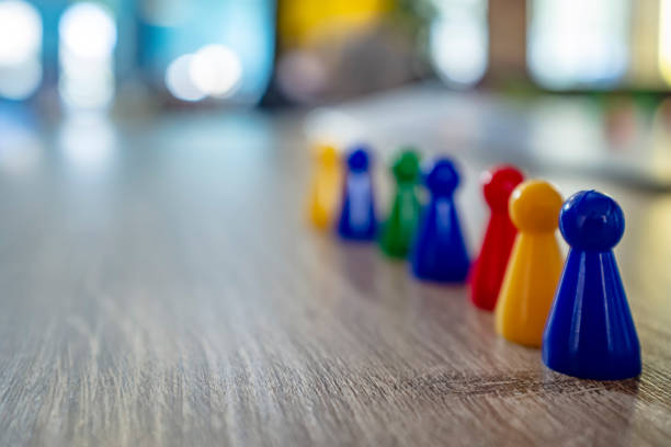 istock Child put in one row multicolored plastic chips from a board game on a wooden table, in natural light, on a blurred background. 1141010177