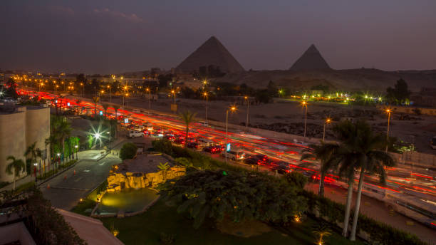 el tráfico del cairo y ver las pirámides por la noche - pirámide estructura de edificio fotografías e imágenes de stock