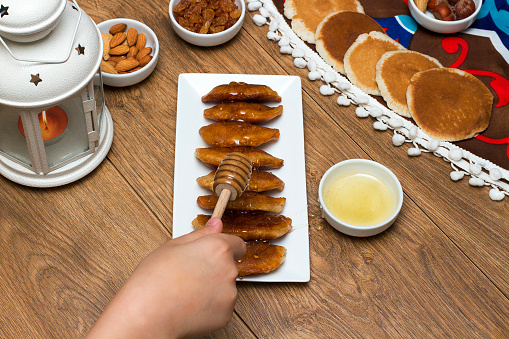 Pouring honey on Qatayef - Traditional middle eastern sweets , usually eaten in Muslims holy month : Ramadan