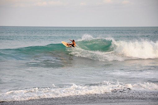 Jaco Beach, Pacific Coast, Costa Rica, March, 21, 2018: A surfer rides a wave at Jaco Beach, Costa Rica.