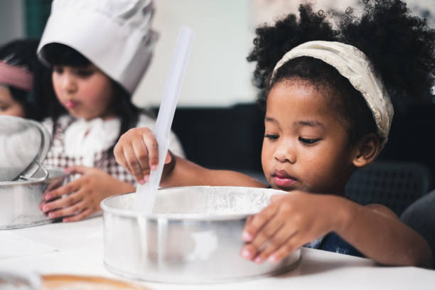 istock Group diversity kids girl making cake bakery in kitchen 1141029671