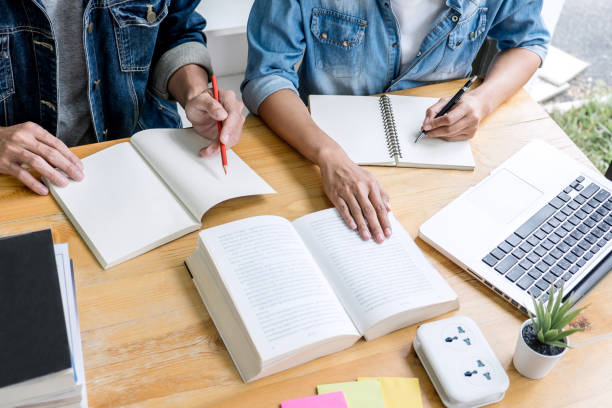 istock Education, teaching, learning, technology and people concept. Two high school students or classmates with helps friend do homeworks learning in classroom, Tutor books with friends 1141029728