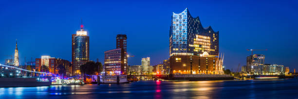 Hamburg night lights over Hafen City Elbphilhamonie city waterfront Germany Panoramic view across the Elbe to the Elbphilhamonie concert hall and illuminated landmarks of HafenCity, the redeveloped waterfront in the heart of Hamburg, Germany’s vibrant second city. elbphilharmonie photos stock pictures, royalty-free photos & images