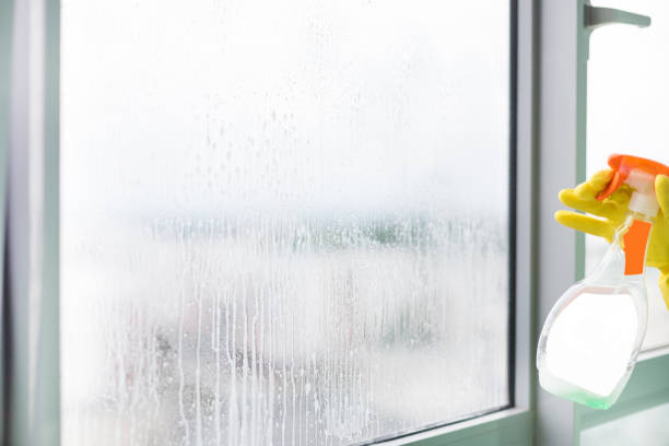 istock worker cleaning soap suds on glass window with squeegee and rag 1141033155