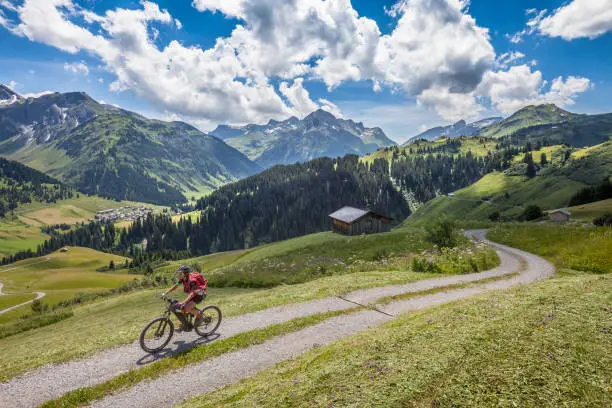 active senior woman, riding her e-mountainbike in the Arlberg area near the famous village of Lech, Tirol, Austrian Alps
