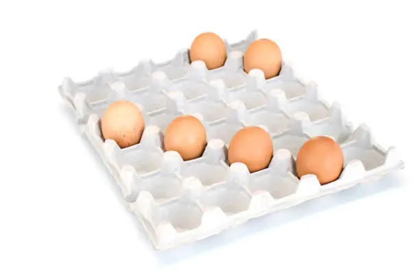 Photo of Isolated close-up of six brown chicken eggs lying in a cardboard tray on the diagonals. Easter concept.