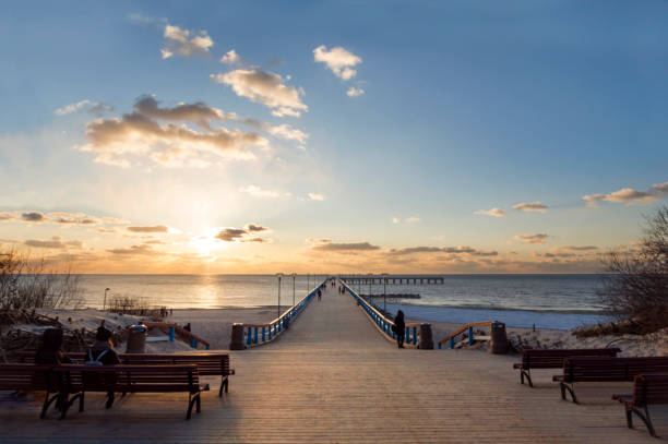 sunset and vacationers on the bridge of palanga on the baltic sea in klaipeda, lithuania - klaipeda imagens e fotografias de stock