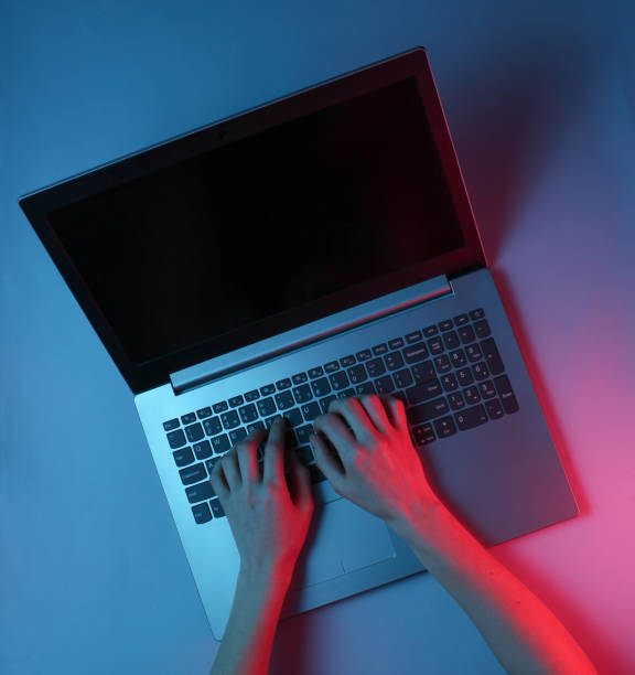 istock Hacker. Online worker. Night work at the laptop. Female hands are typing over a laptop. Red blue neon light 1141039993