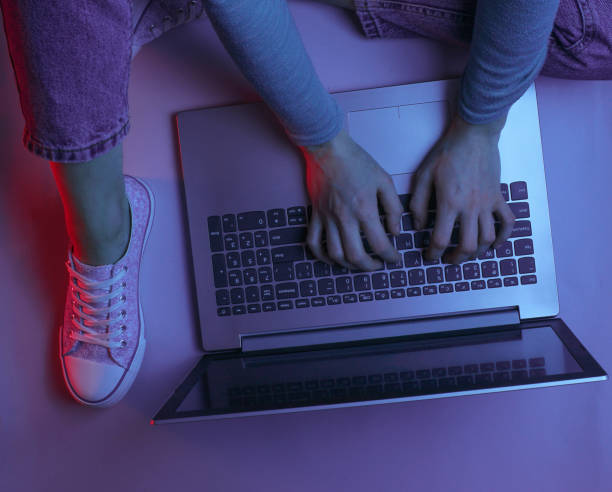 istock Hacker. Online worker. Night work at the laptop. Female hands are typing over a laptop. Dark purple red neon light 1141040033