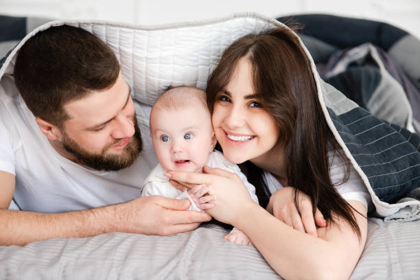 istock Young smiling family with infant under blanket 1141041349