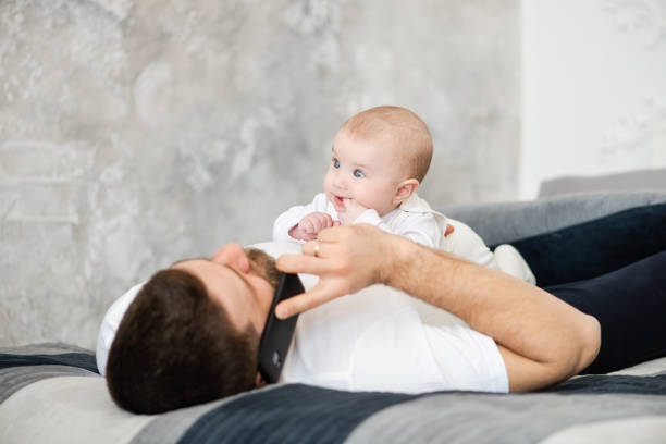 istock Father talks by phone and play with baby 1141041560