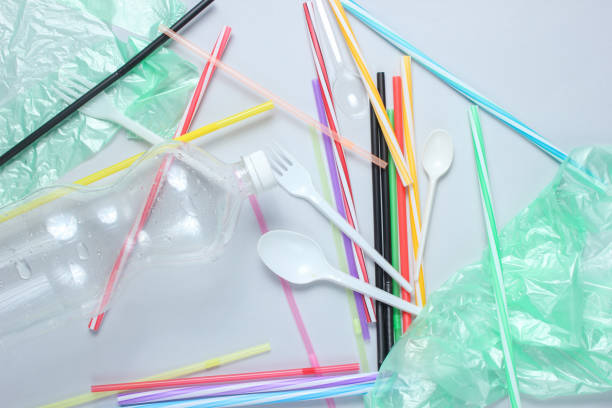 istock The concept of pollution plastic and polyethylene environment. Cellophane bag, plastic bottle, disposable forks and spoons, cocktail tubes on gray background. Top view 1141041702