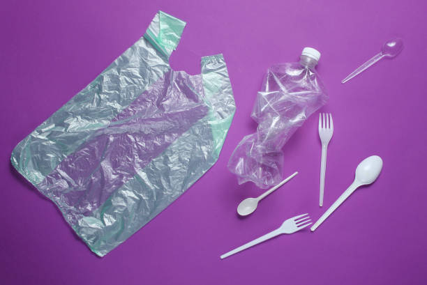 istock The concept of pollution plastic environment. Cellophane bag, plastic bottle, disposable forks and spoons, cocktail tubes on purple background. Top view 1141041709
