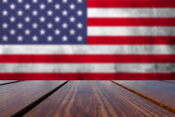 istock Wood Table Top Background and USA flag on wall. 1141043041