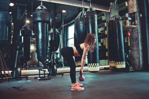 istock Functional training. Woman doing deadlift exercise with kettlebell indoors at gym 1141043064